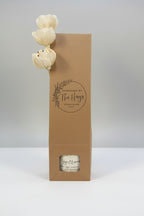 Kraft paper packaging with a small jar and decorative flowers on a light gray background